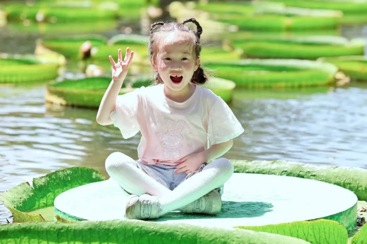 Children have fun seated on royal water lily leaves in Wuhan Botanical Garden