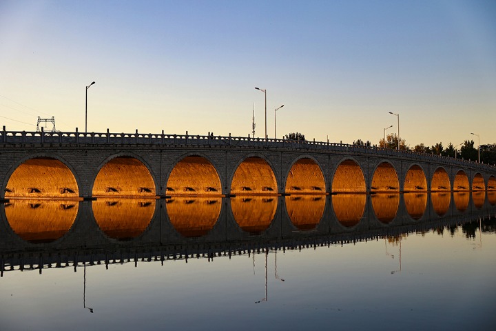 Setting sun shining through bridge draws photographers