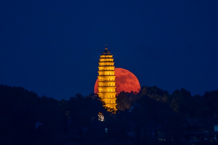 Spectacular super blood moon passes by the white pagoda in Sichuan