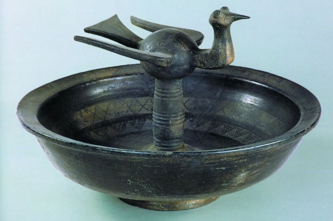 Ancient black pottery plate captures a flying swallow