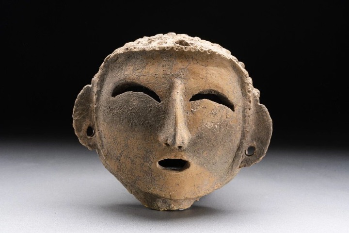 A pottery head carries a gentle smile from 5,000 years ago